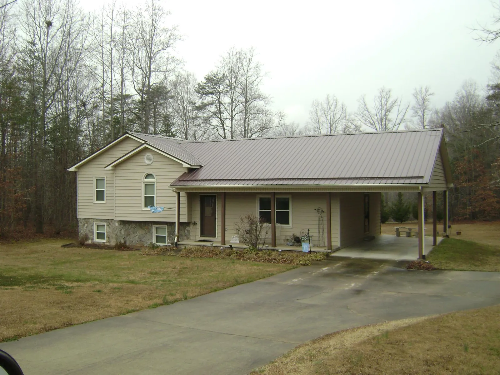 Brown metal roof on a tan split level home with an attached carport in Manchester